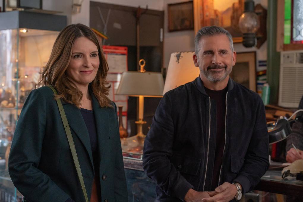 A middle aged white woman and white man stand politely smiling in an antiques store.